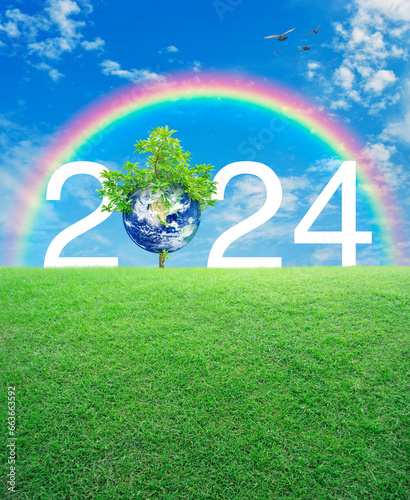 2024 white text with planet and tree on green grass field over rainbow, birds and blue sky, Happy new year 2024 ecological cover, Save the earth concept, Elements of this image furnished by NASA