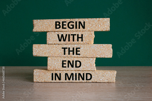 Begin in end of mind symbol. Concept words Begin with the end in mind on brick blocks. Beautiful wooden table green background. Business begin in end of mind concept. Copy space.