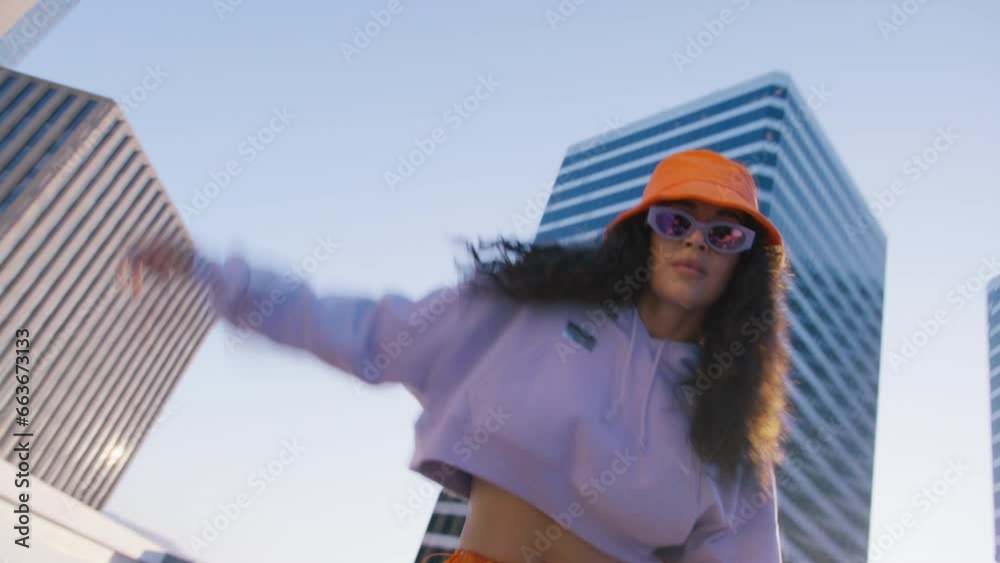 African american girl performer dancing on rooftop in downtown at summer evening. Flexible young woman moving body smoothly enjoying modern music beat. Curly model performing contemporary street style