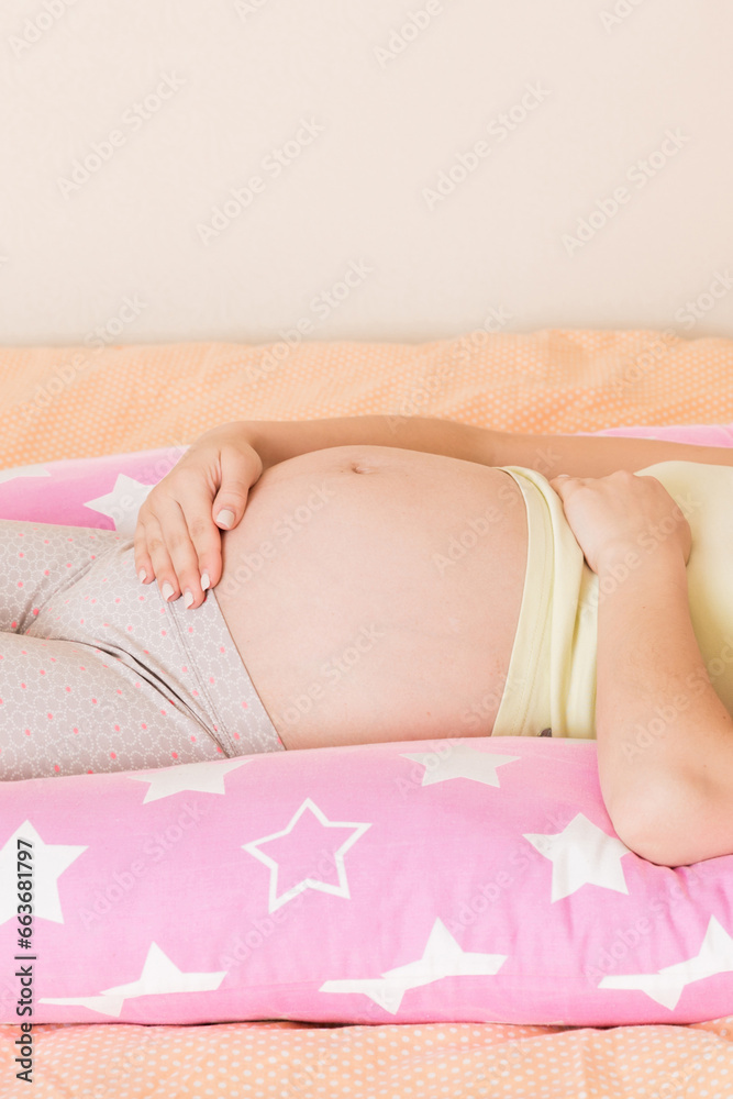 Beautiful pregnant woman sleeping with body pillow on bed Beautiful pregnant woman sleeping with body pillow on bed