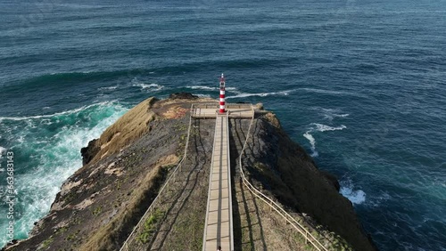 Fenais da Ajuda lighthouse on rocky promontory, Sao Miguel, aerial pullback photo