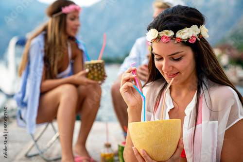 Happy young woman enjoying a tropical cocktail on beach. Travel and summer vacation concept.