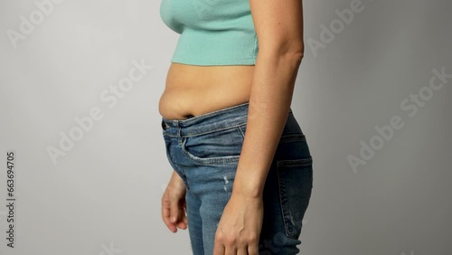 Young woman with obesity pulling and fitting small tight jeans