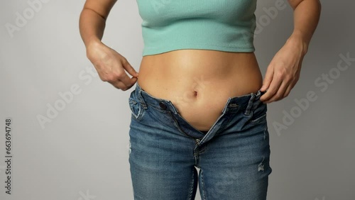 Young woman with obesity pulling and fitting small tight jeans