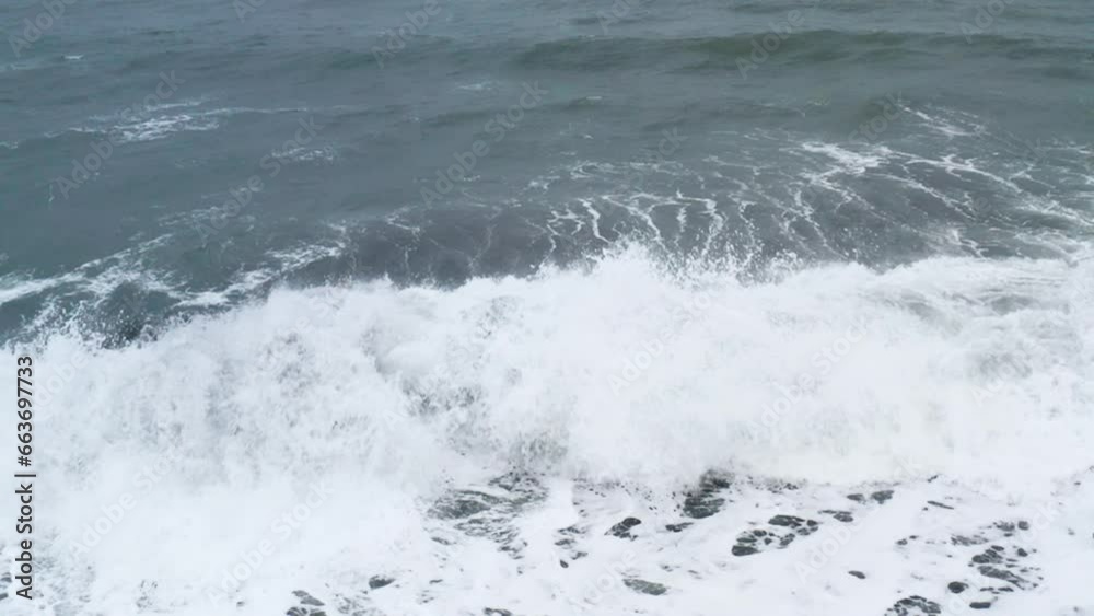 Stunning drone shot of waves breaking on a beautiful ice rock at Diamond Beach in Iceland (slow motion) Stunning drone shot of waves breaking on a beautiful ice rock at Diamond Beach in Iceland (slow motion)