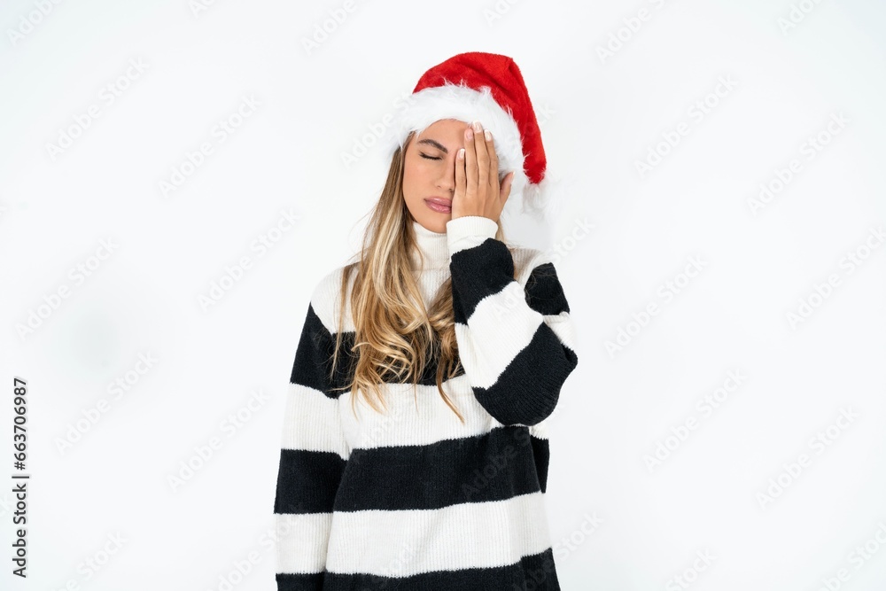 Tired overworked Beautiful hispanic woman wearing christmas hat has sleepy expression, gloomy look, covers face with hand, has eyes shut, gasps from tiredness, fatigue after party Tired overworked Beautiful hispanic woman wearing christmas hat has sleepy expression, gloomy look, covers face with hand, has eyes shut, gasps from tiredness, fatigue after party