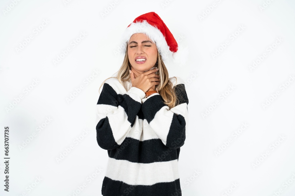 Beautiful hispanic woman wearing christmas hat and striped knitted sweater shouting suffocate because painful strangle. Health problem. Asphyxiate and suicide concept. Beautiful hispanic woman wearing christmas hat and striped knitted sweater shouting suffocate because painful strangle. Health problem. Asphyxiate and suicide concept.