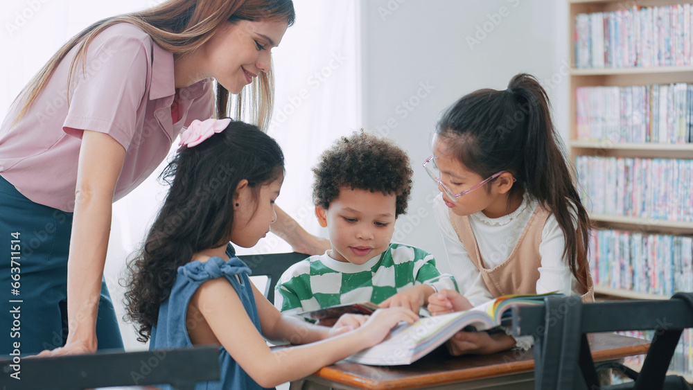Obraz premium Female teacher helping school kids in classroom. Elementary woman teacher teaching students doing the lesson in classroom. Education knowledge concept