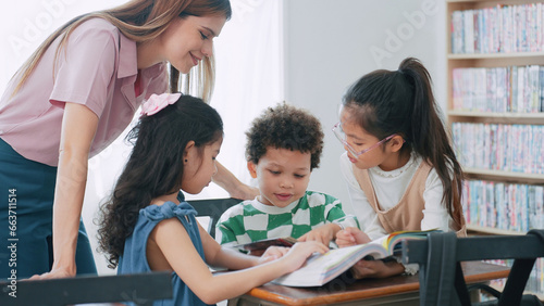 Female teacher helping school kids in classroom. Elementary woman teacher teaching students doing the lesson in classroom. Education knowledge concept