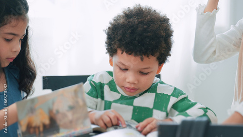 Happy African american kindergarten student reading a books for learning in library at school. Child boy in school library. Education and learning concept