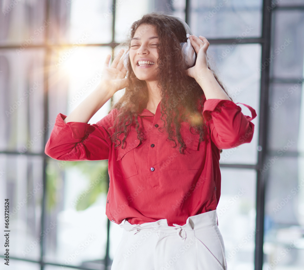 Fototapeta premium Beautiful smiling young woman in headphones in modern office