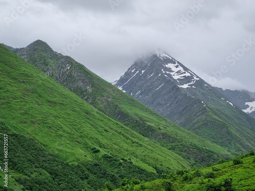Snow-Capped Mountains with Green and Dry Grass  Clouds  and a Stunning Sky