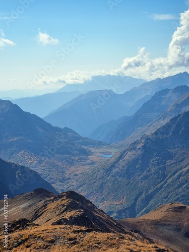 Snow-Capped Mountains with Green and Dry Grass, Clouds, and a Stunning Sky