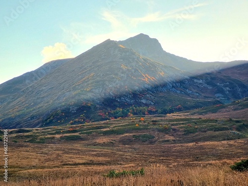 Snow-Capped Mountains with Green and Dry Grass, Clouds, and a Stunning Sky