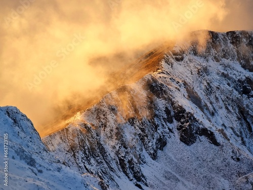 Snow-Capped Mountains with Green and Dry Grass, Clouds, and a Stunning Sky