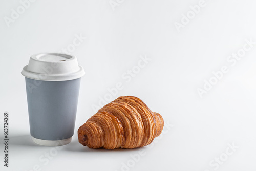 Hot drink in a craft glass and a lush delicious croissant on a white background