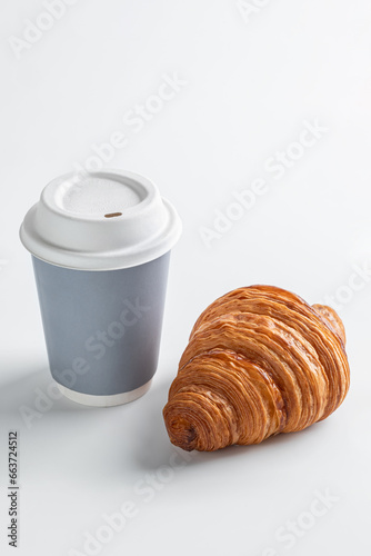Hot coffee in a craft cup and a lush delicious croissant on a light background