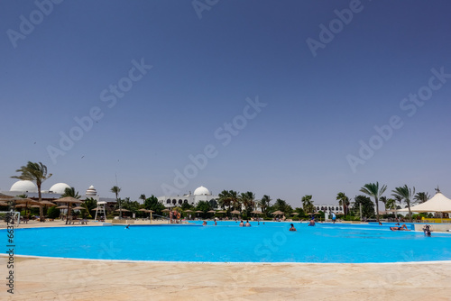 deep blue water in a pool with palm trees and lot of people on vacation