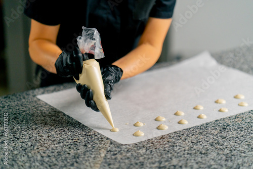 Fotografija A confectioner squeezes chocolate from a pastry bag in the form of natural candi