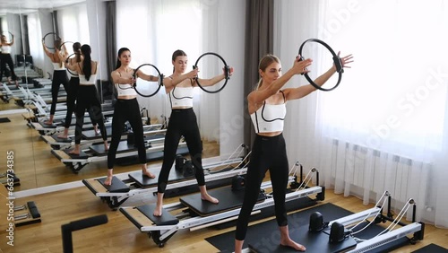 Group of women exercises during a class using pilates reformer beds in studio. Lifestyle and fitness concept. photo
