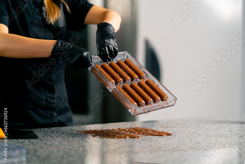 Drops of melted hot chocolate that pours out of an inverted mold for making candies in confectionery shop photo