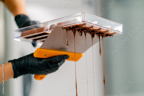 Canvas Print Drops of melted hot chocolate that pours out of an inverted mold for making cand