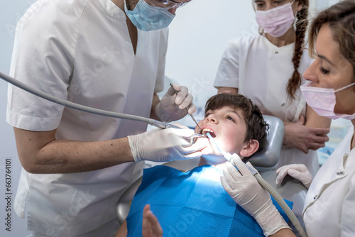 Team of dentists treating a young boy for orthodontics in the dentist's clinic