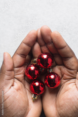 Overhead view of red Christmas ornaments in hands, sparkly red christmas tree baubles in woman's hands, flatlay of red christmas tree decoration
