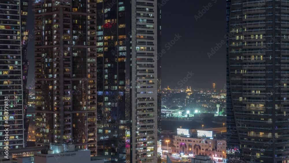 Business bay district skyline with modern architecture timelapse night from above. Aerial view of Dubai skyscrapers and illuminated towers near main highway. Multi-storey parkings and light in windows Business bay district skyline with modern architecture timelapse night from above. Aerial view of Dubai skyscrapers and illuminated towers near main highway. Multi-storey parkings and light in windows