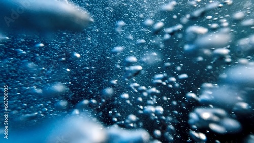 Air bubbles ascending from the ocean floor to the water's surface in slow motion, accompanied by a diver's release of air. Abstract and serene natural background