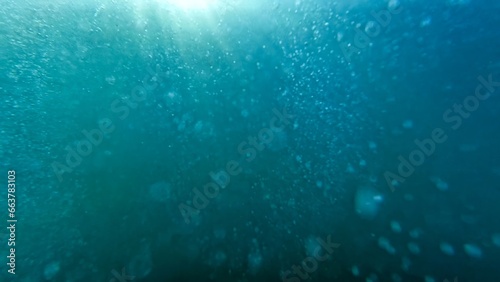 Air bubbles rising from the sea bottom up to water surface. Diver releasing air. Abstract natural background or backdrop