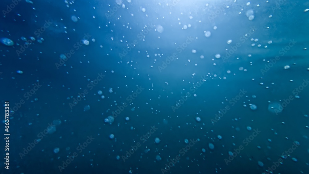 Underwater shot of sun rays shining through clear sea water with rising up air bubbles Underwater shot of sun rays shining through clear sea water with rising up air bubbles