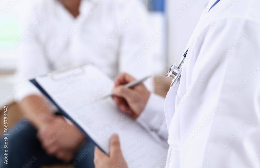 Male doctor hand hold silver pen and showing pad. Physical agreement form signature disease prevention ward round reception consent contract sign prescribe remedy healthy lifestyle concept