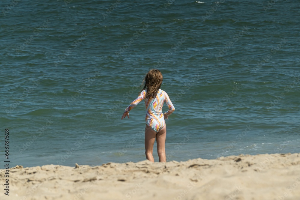 a young girl on the beach playing with a frisbee