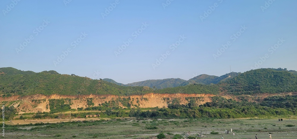 Scenic view of a countryside farm field with green grass and majestic mountains in the background