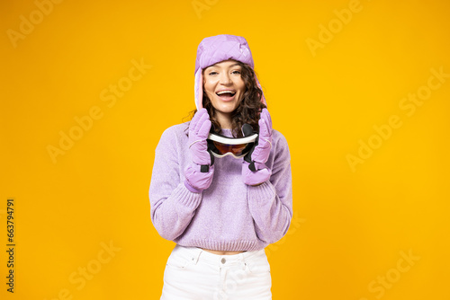 A woman in a warm ski suit on a yellow background.