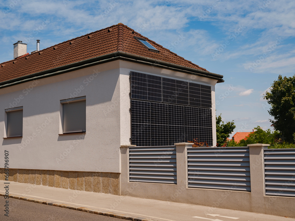 Solar photovoltaic panels on house wall. Modern country house with self-sustaining energy system. Suburb of Vienna, Austria. Idea harnessing clean and sustainable energy, saving money on electricity Solar photovoltaic panels on house wall. Modern country house with self-sustaining energy system. Suburb of Vienna, Austria. Idea harnessing clean and sustainable energy, saving money on electricity