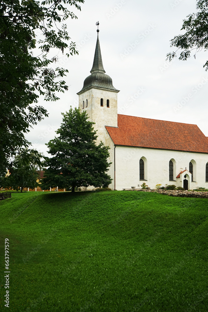 Old white stone church against the backdrop of a lawn and trees Old white stone church against the backdrop of a lawn and trees