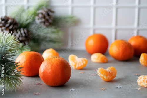 Bright orange tangerines in a glass vase on a gray table. Christmas and New Year concept.
