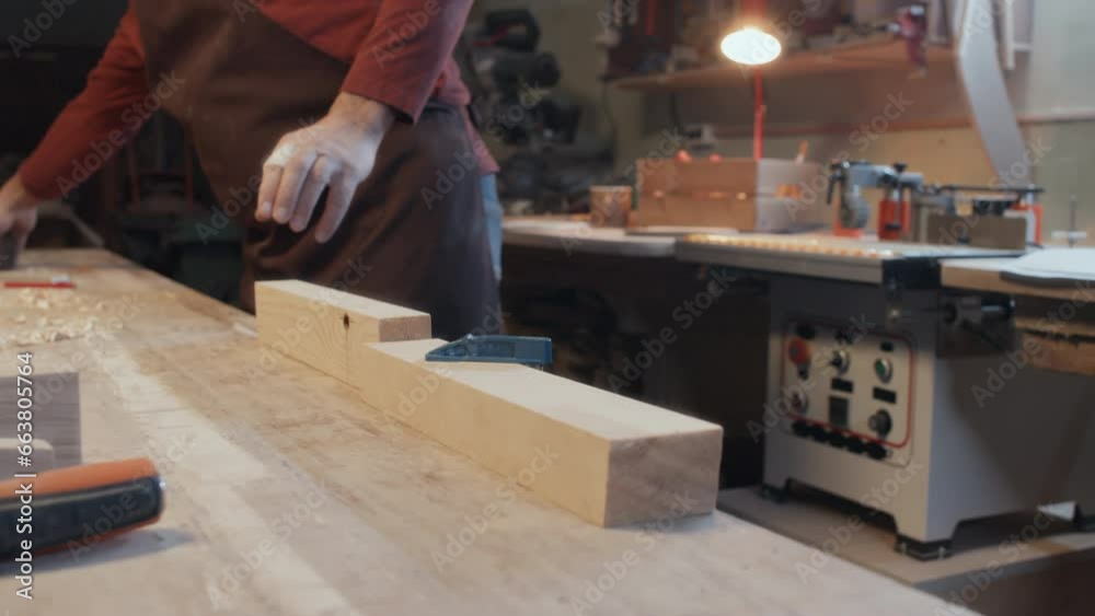 Selective focus medium close-up of piece of wood secured with clamp to table while male hands holding plane Selective focus medium close-up of piece of wood secured with clamp to table while male hands holding plane