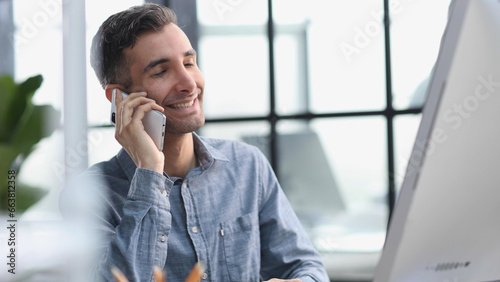 Sure, we can do that for you. A young businessman talking on the phone while seated at his desk.