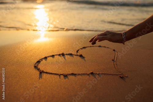 Women s hands draw a heart on the sand. love and relationships.