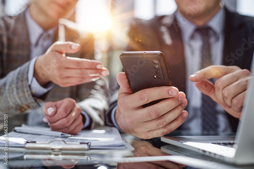 manager uses smartphone while sitting at table with colleague