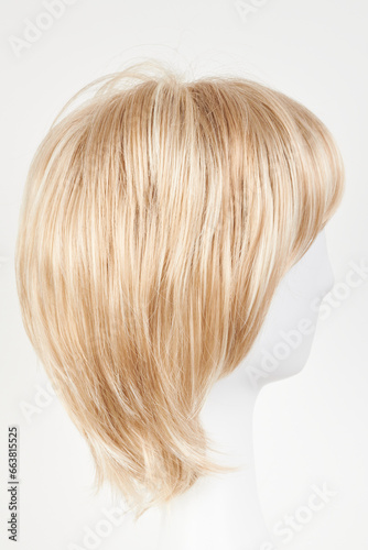 Natural looking blonde fair wig on white mannequin head. Short hair cut on the plastic wig holder isolated on white background  side view.