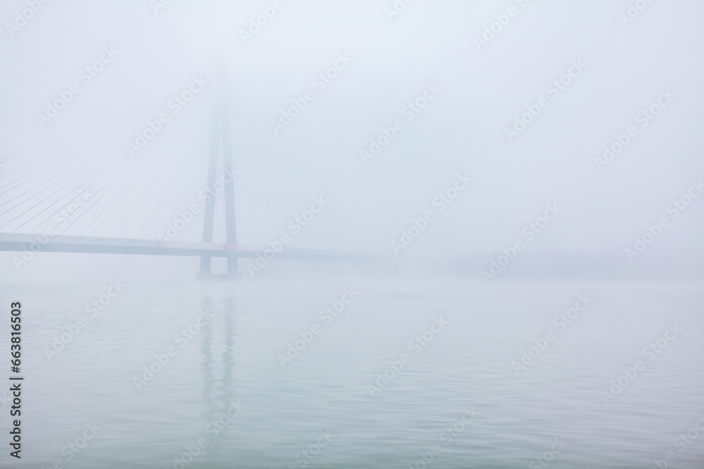Bridge over the river in a foggy winter morning