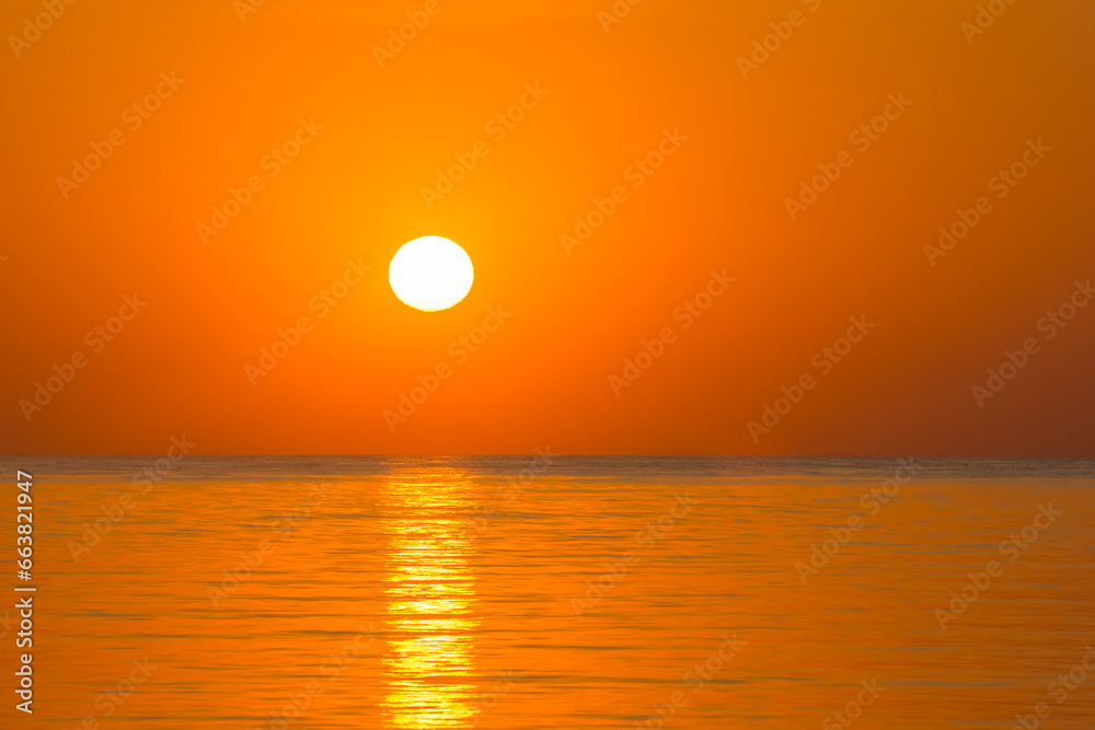white hot sun with orange sky and sea during sunrise