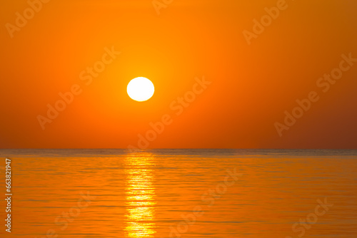Fototapeta Naklejka Na Ścianę i Meble -  white hot sun with orange sky and sea during sunrise