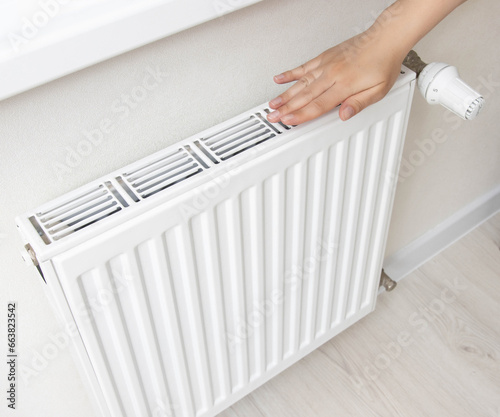 Wallpaper Mural The girl holds her hand near the radiator in the room. The concept of comfortable temperature in the winter in the apartment. Gas heating, sanctions on energy resources. Copy space for text Torontodigital.ca