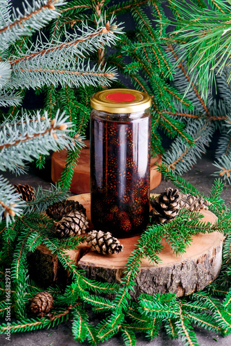 Jam from young pine cones in syrup on a background with pine branches