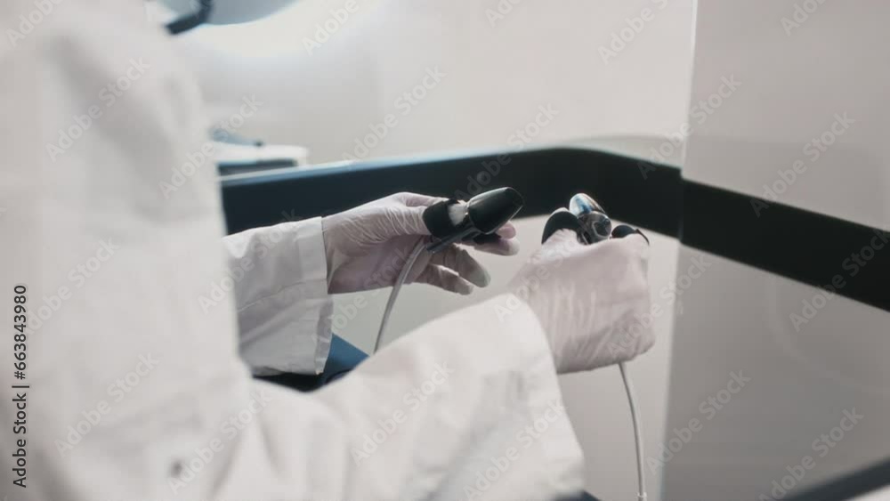 A medic girl controls a medical robot Da Vinci. A woman doctor performs an innovative remote operation. A female holds a surgical scalpel control tool in her hands. Cancer treatment in virtual reality
